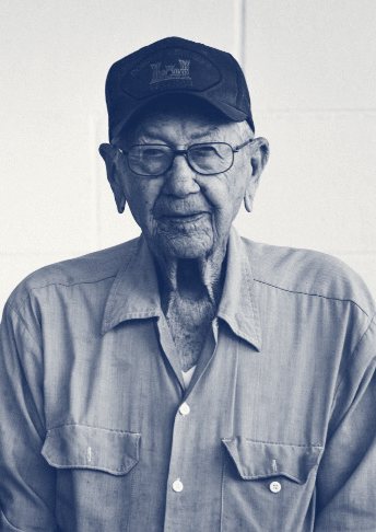 Black and white portrait of Papa in his later years, wearing a cap, glasses, and a work shirt
